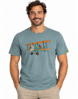 A man wearing a slate blue crewneck t-shirt with a vintage biplane graphic on the chest, paired with khaki pants, against a plain white background.