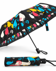 A compact folding umbrella shown open and closed on a plain white background. The umbrella features a black base with a colourful abstract bird pattern in blue, yellow, pink, white, and red.