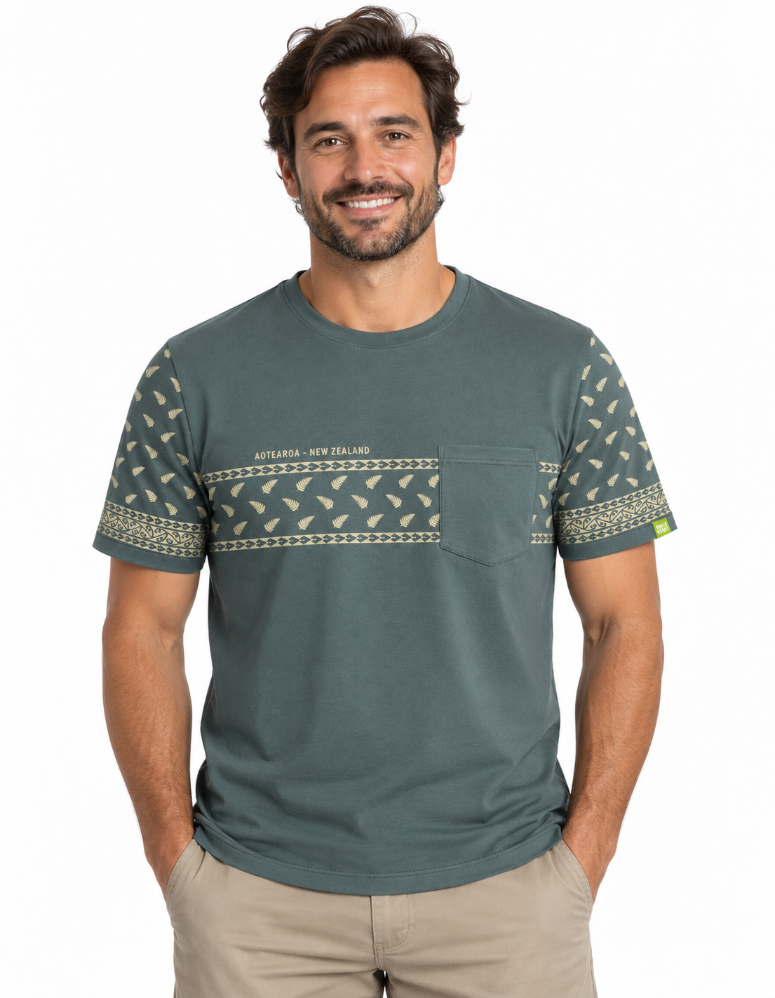 A man wearing a muted green short-sleeve t-shirt with a chest pocket and a horizontal patterned band across the chest and sleeves, paired with khaki pants, against a plain white background.