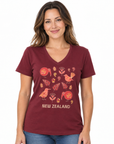 A woman wearing a maroon V-neck t-shirt with a New Zealand bird and leaf graphic print, paired with blue jeans, against a plain white background.