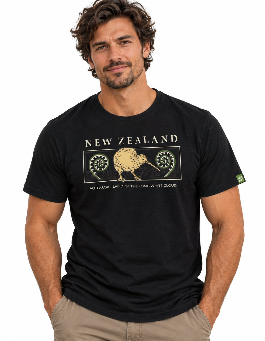 A man wearing a black short-sleeve graphic t-shirt with a gold kiwi bird and 'NEW ZEALAND' text on the chest, paired with khaki pants, against a plain white background.