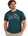 A man wearing a dark teal heathered t-shirt with a Polynesian wave graphic in white and red, paired with khaki pants, against a plain white background.