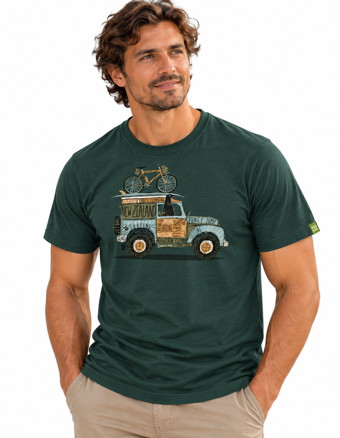 A man wearing a dark green crewneck t-shirt with a vintage truck and bicycle graphic on the front, paired with khaki pants, against a plain white background.
