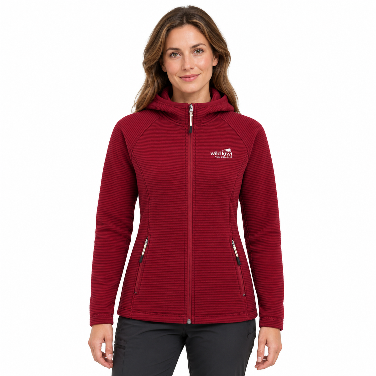 A woman wearing a textured red hooded zip-up jacket with a white embroidered logo on the left chest, paired with dark gray pants, against a plain white background.