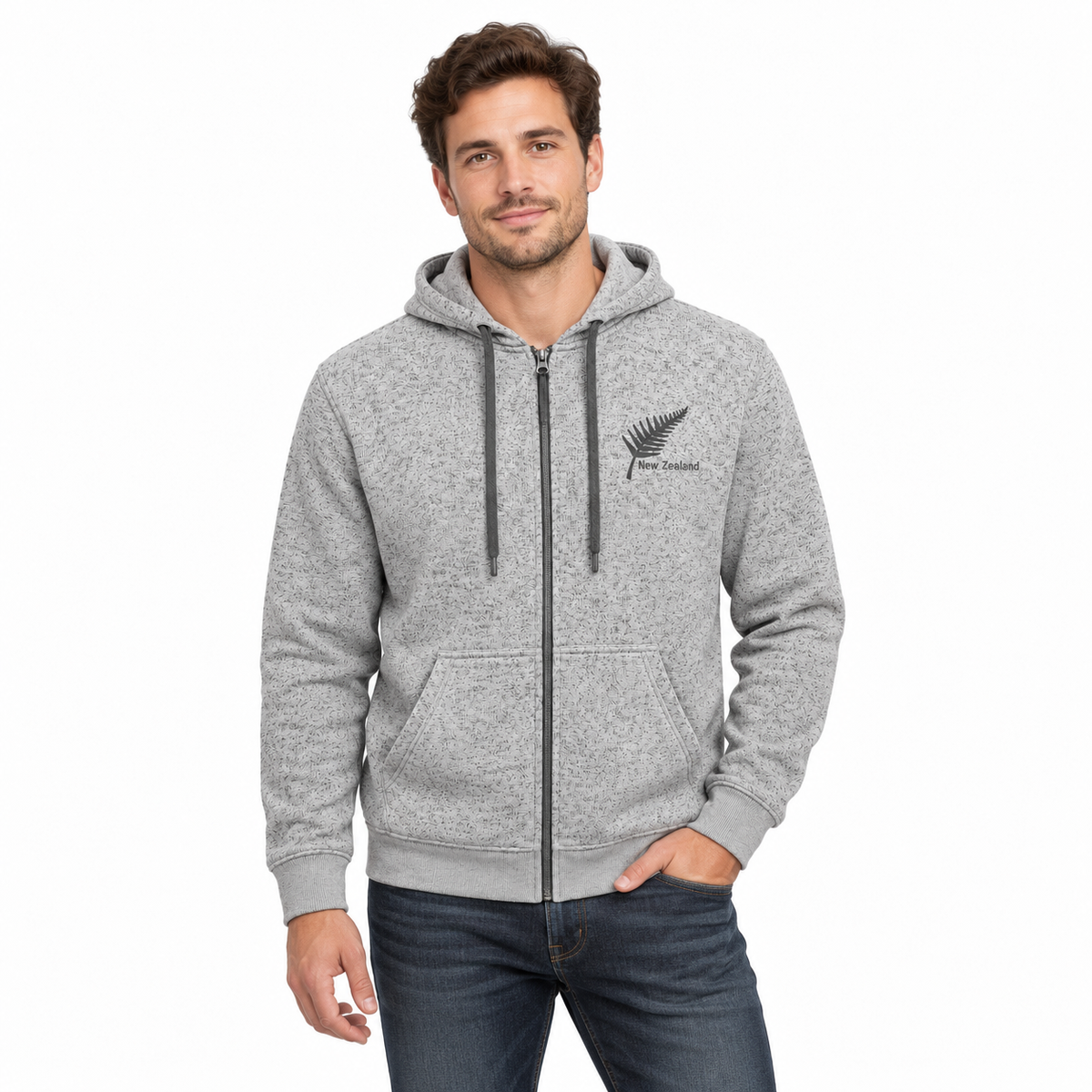 A man wearing a heather gray full-zip hoodie with a black fern logo and 'Wanganui' text on the left chest, paired with dark blue jeans, against a plain white background.