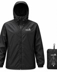 A black hooded waterproof jacket shown front-facing on a white background, alongside its matching black compact storage pouch with white printed branding and a small size label.