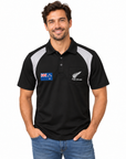 A man wearing a black short-sleeve polo shirt with grey shoulder panels and a white New Zealand All Blacks logo on the chest pocket, photographed against a plain white background.