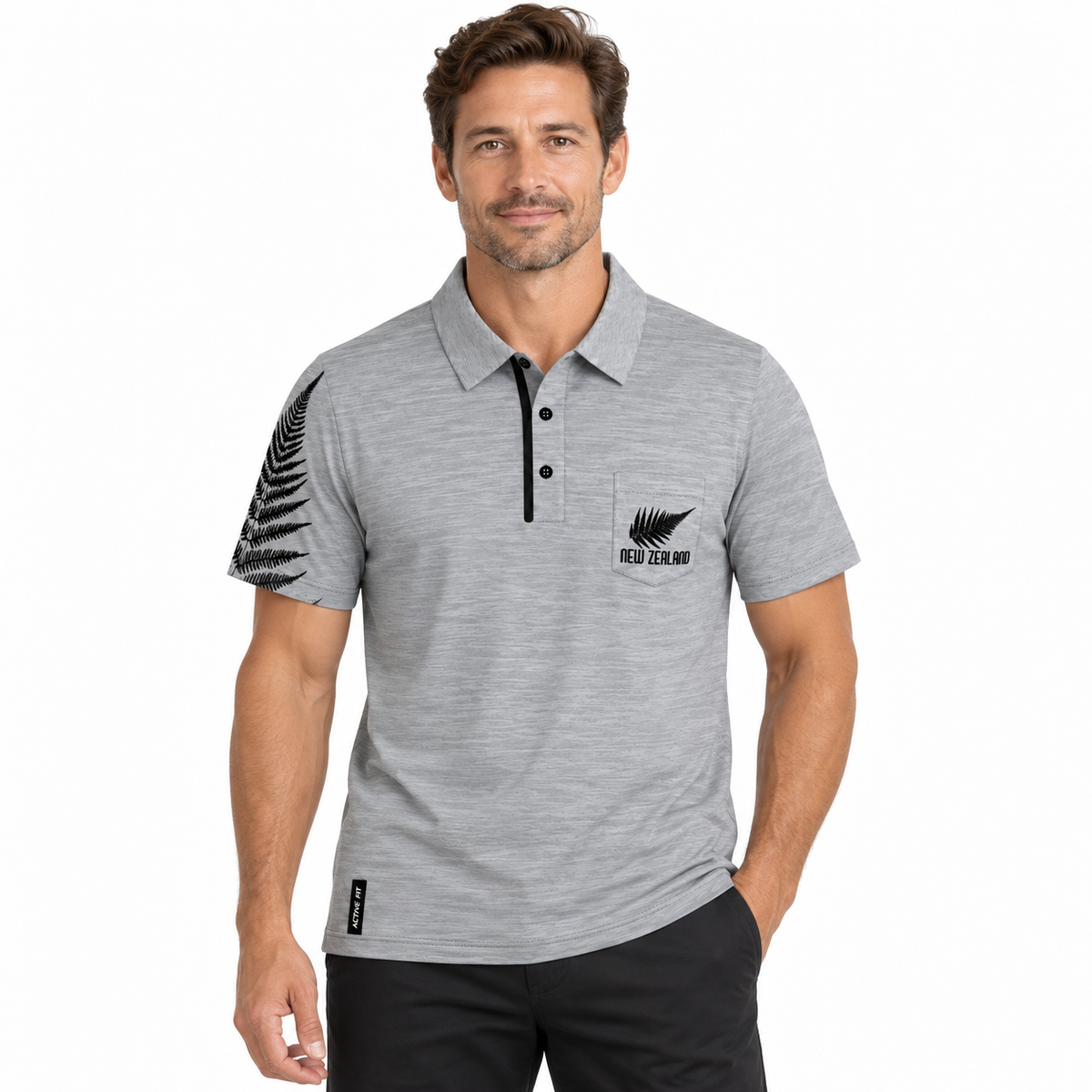 A man wearing a heather gray short-sleeve polo shirt with a black fern leaf graphic on the sleeve and a black New Zealand silver fern logo on the chest, paired with black pants, against a plain white background.