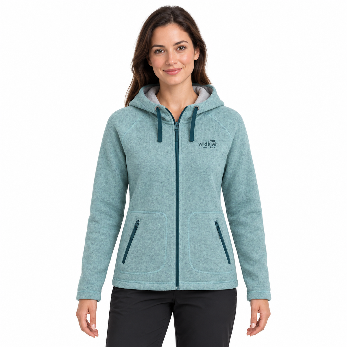 A woman wearing a light blue heather zip-up hoodie with dark teal drawstrings, zippers, and a small 'WILD AFRICA' logo on the left chest, paired with black pants, against a plain white background.