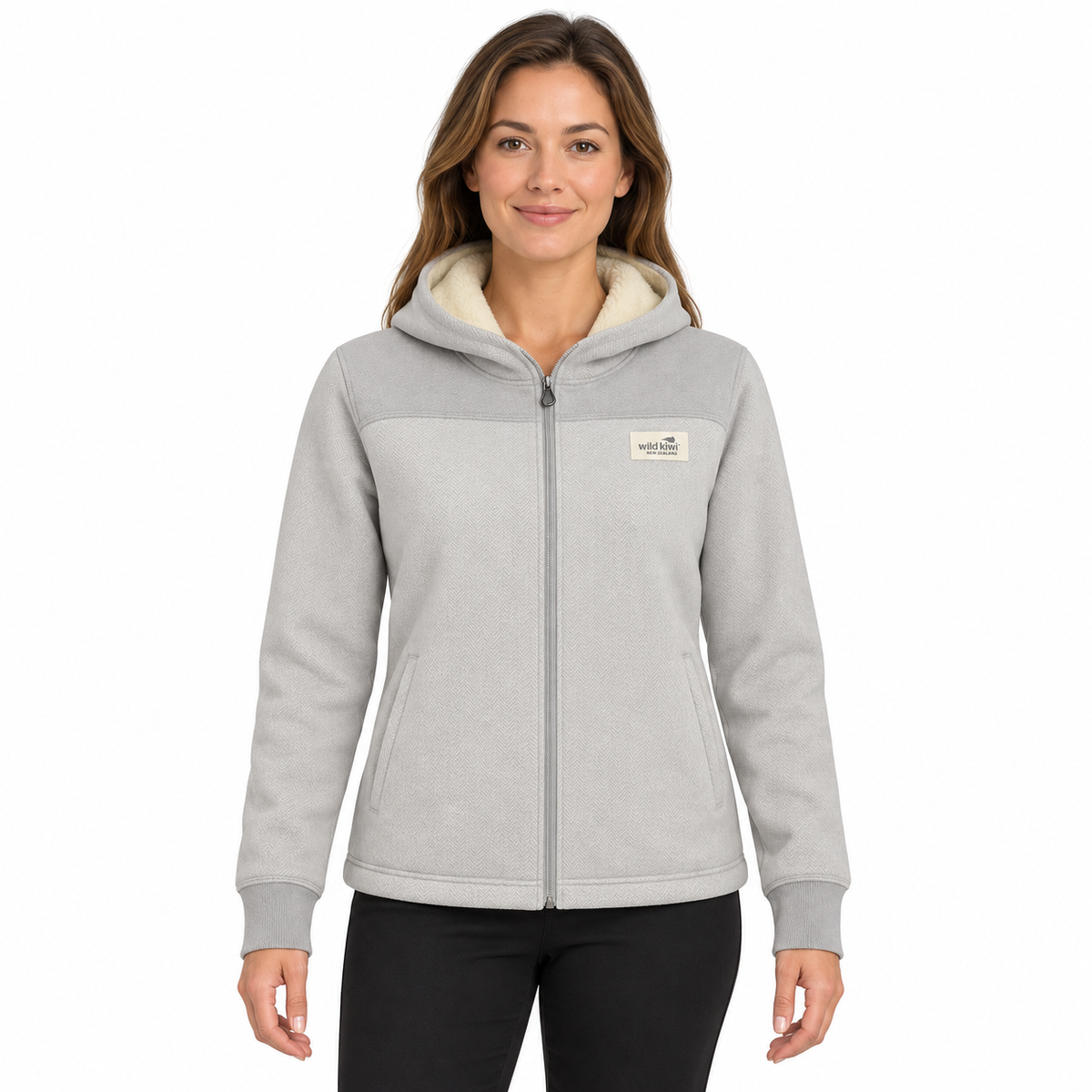 A woman wearing a light gray zip-up hoodie with a cream sherpa-lined hood and a small 'The North Face' logo patch on the left chest, set against a plain white background.