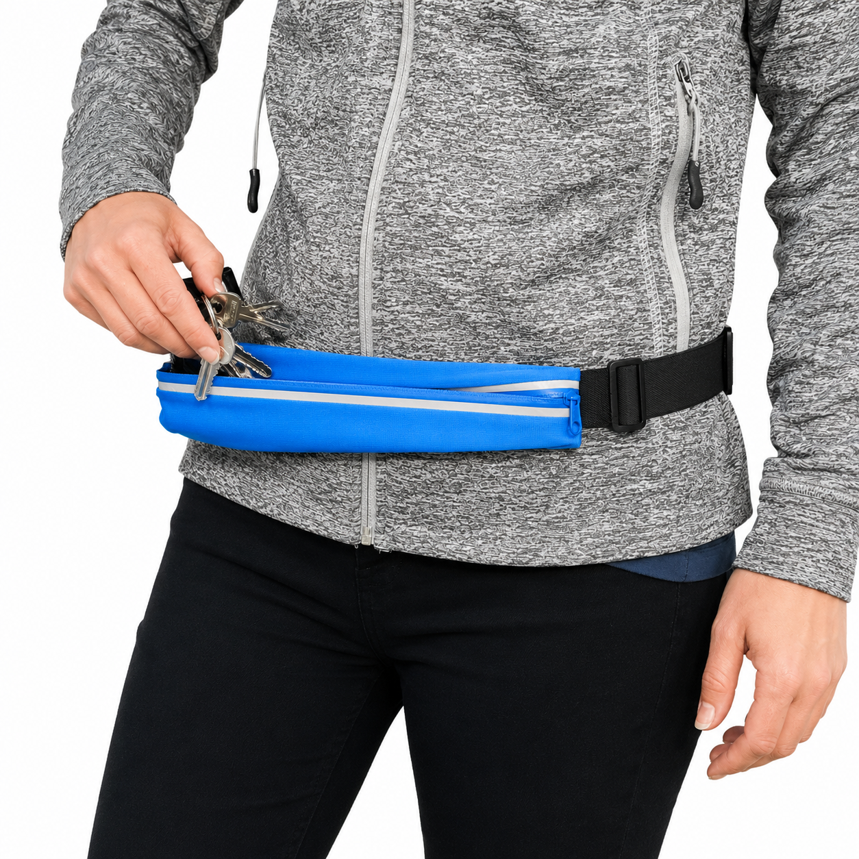 A person wearing a gray heathered zip-up jacket and black pants carries a bright blue waist bag with a black buckle while inserting keys into the front pocket.