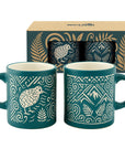 Two teal ceramic mugs with white tribal-style patterns and a matching gift box behind them, photographed on a clean white background.