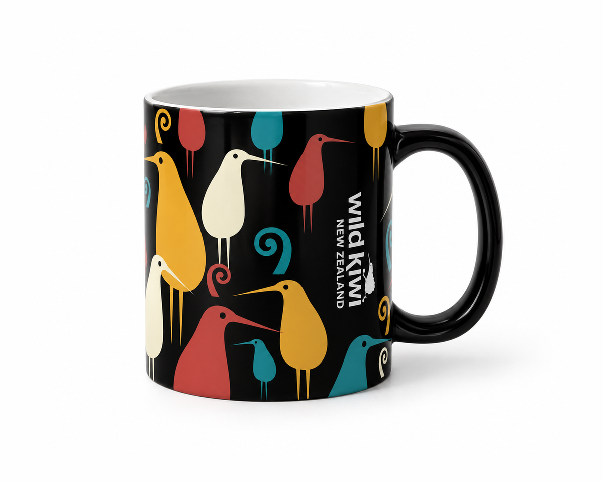 A black ceramic mug featuring a colourful pattern of stylised New Zealand birds in yellow, teal, pink, and cream, with the text 'wild kiwi NEW ZEALAND' printed vertically on the side.