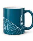 A dark teal ceramic mug featuring a white line art illustration of mountain peaks and the vertical text 'Wild Kiwi New Zealand' on the side, shown against a plain white background.