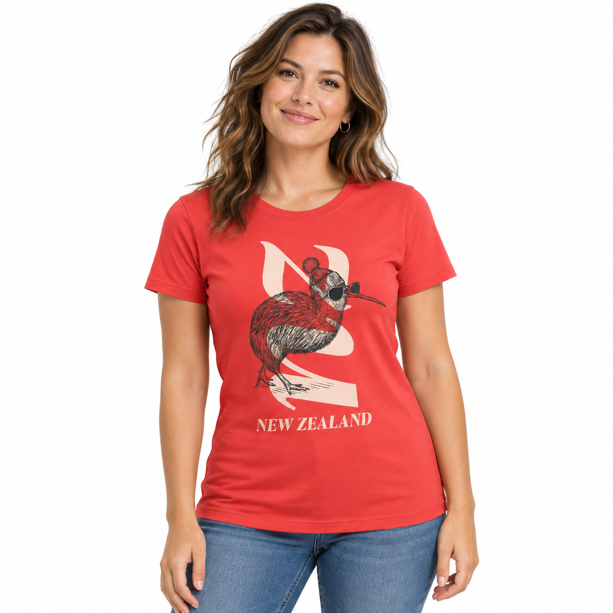 A woman wearing a red short-sleeve graphic t-shirt with a kiwi bird and New Zealand map design, paired with dark blue jeans, against a plain white background.